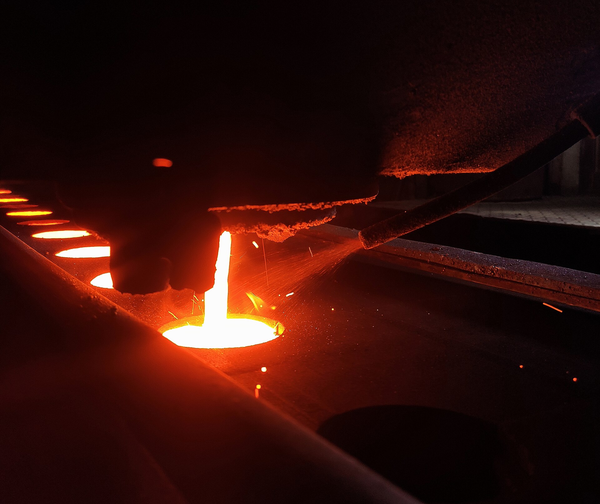Molten cast iron poured into a green sand mold in a foundry