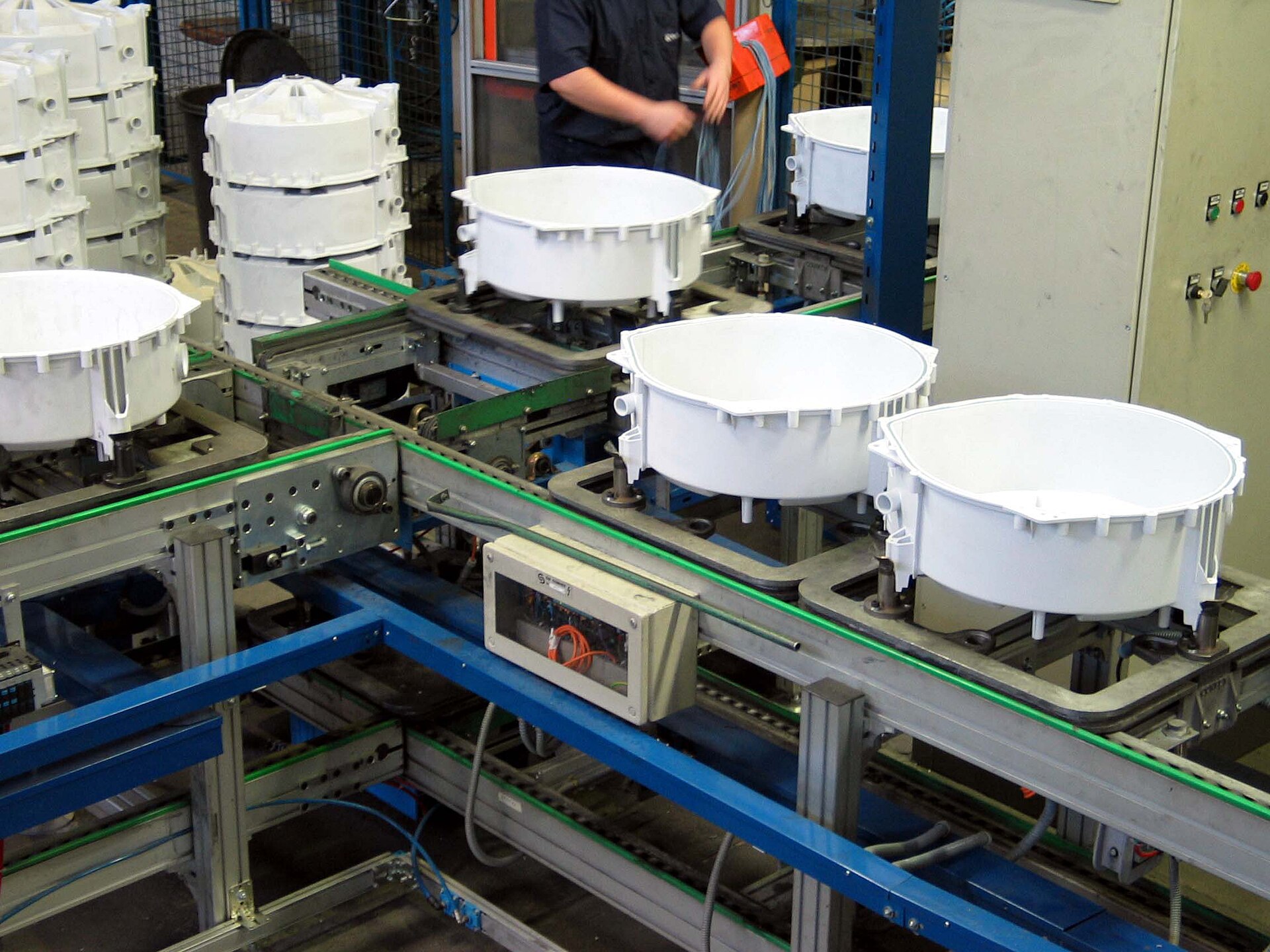 Chain conveyor carrying white molded parts through an assembly junction